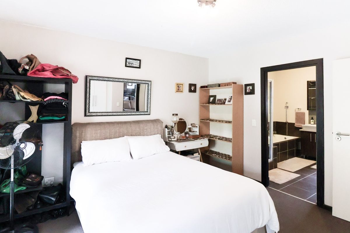 A bedroom featuring an en-suite bathroom with tiled flooring, a built-in bathtub, and a vanity cabinet, providing a functional and connected living space.