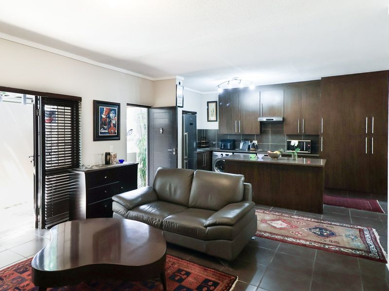 Open-plan living area featuring a modern kitchen with dark wood cabinetry, a central island, and direct access to an outdoor patio area.