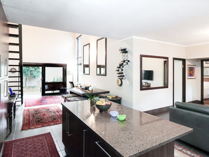 Spacious open-plan living area featuring a modern kitchen island with stone countertops, high ceilings, and direct access to the outdoor patio area.