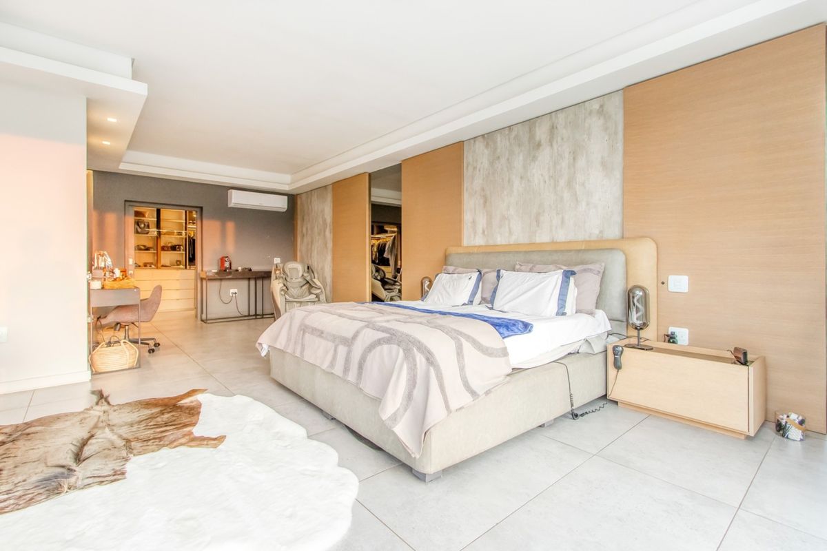 Spacious modern bedroom featuring tiled floors, recessed ceiling lighting, a wall-mounted air conditioning unit, and an integrated walk-in closet area.
