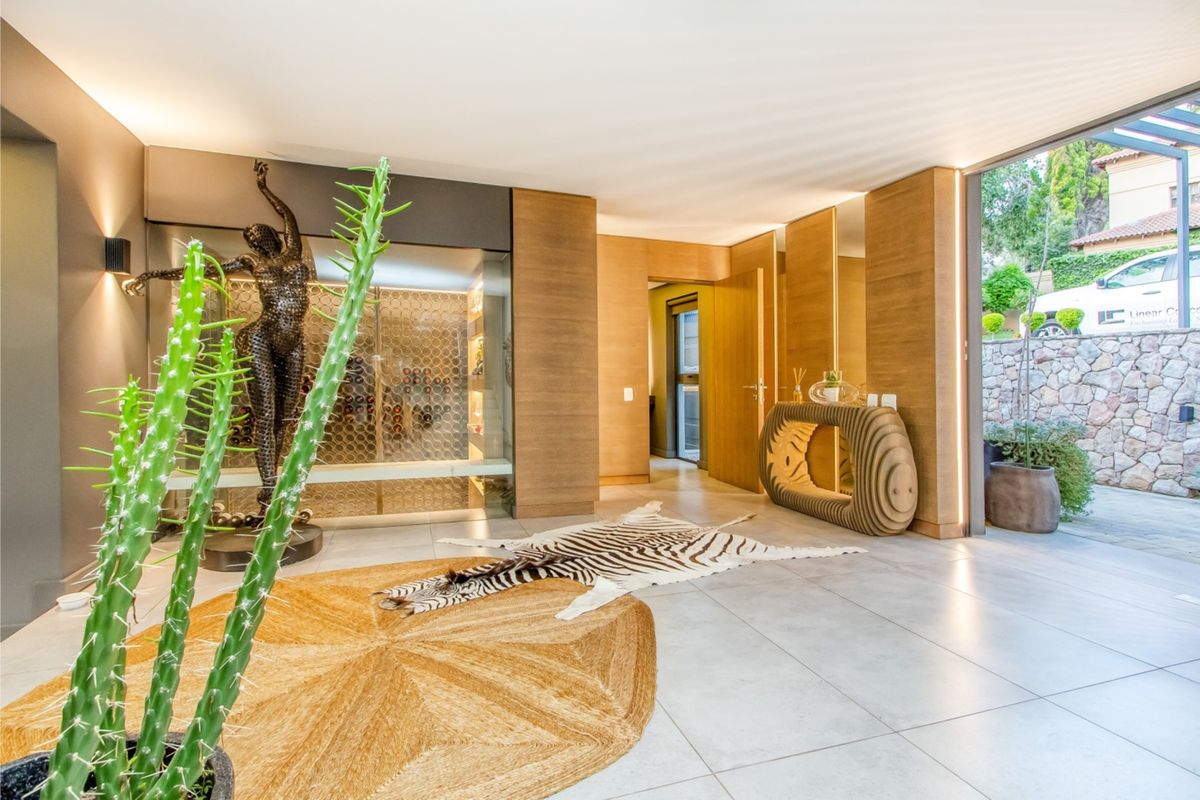Modern living area featuring high-end wood paneling, integrated wine cellar, recessed lighting, and large sliding glass doors opening to an outdoor space.