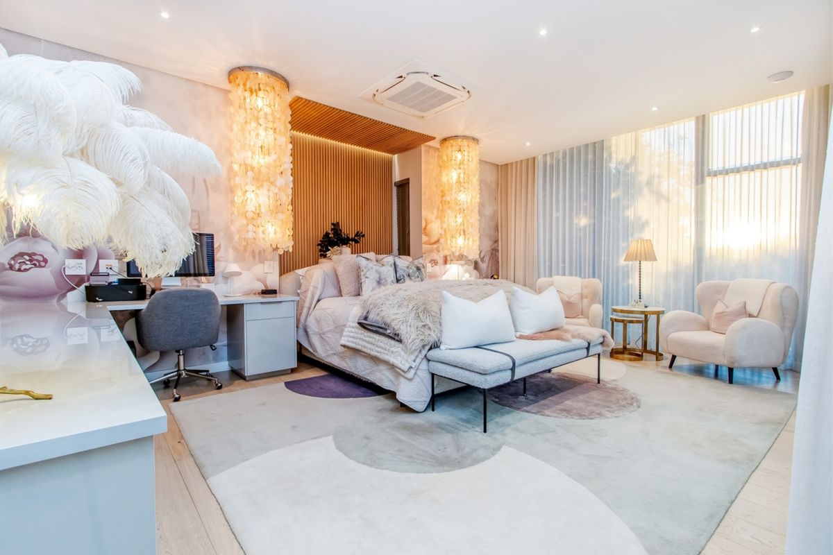 A luxurious, well-appointed bedroom featuring a timber slat feature wall, integrated air conditioning, built-in desk, and large windows with soft natural light.