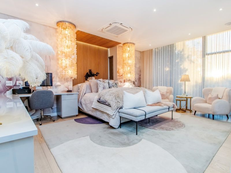 A luxurious, well-appointed bedroom featuring a timber slat feature wall, integrated air conditioning, built-in desk, and large windows with soft natural light.