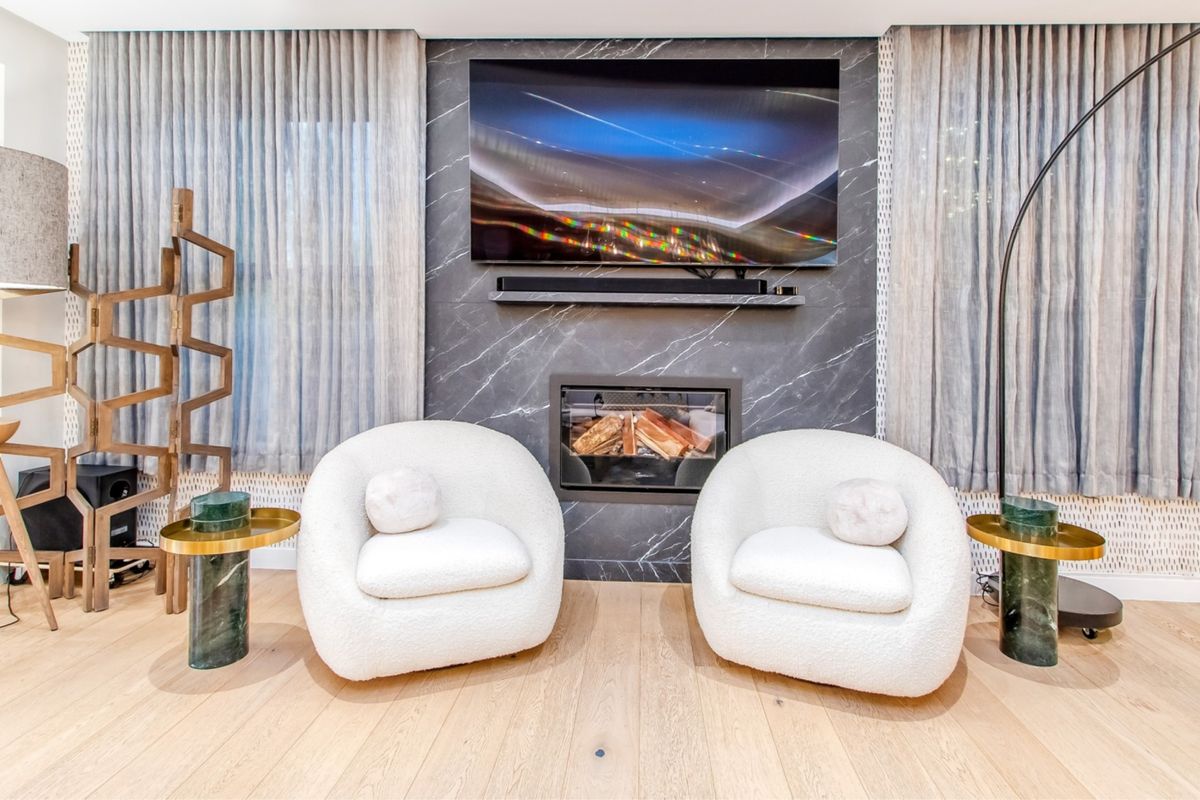 A modern living room featuring a striking marble fireplace surround, integrated fireplace, and high-quality hardwood flooring.