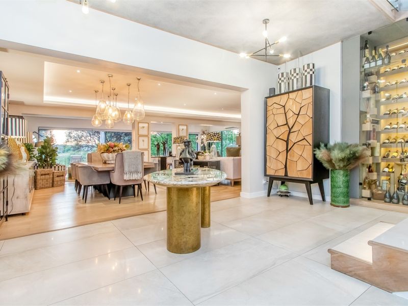 Spacious open-plan living and dining area featuring high-end finishes, recessed lighting, and a sophisticated built-in glass wine display.