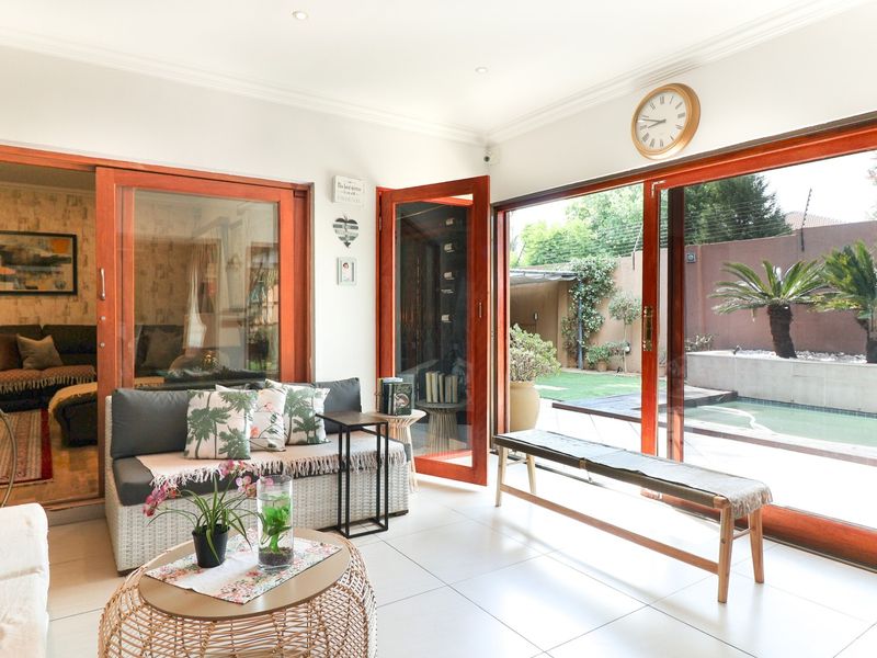 Bright living room featuring large wooden sliding doors that open to a pool area, tiled floors, and recessed lighting.