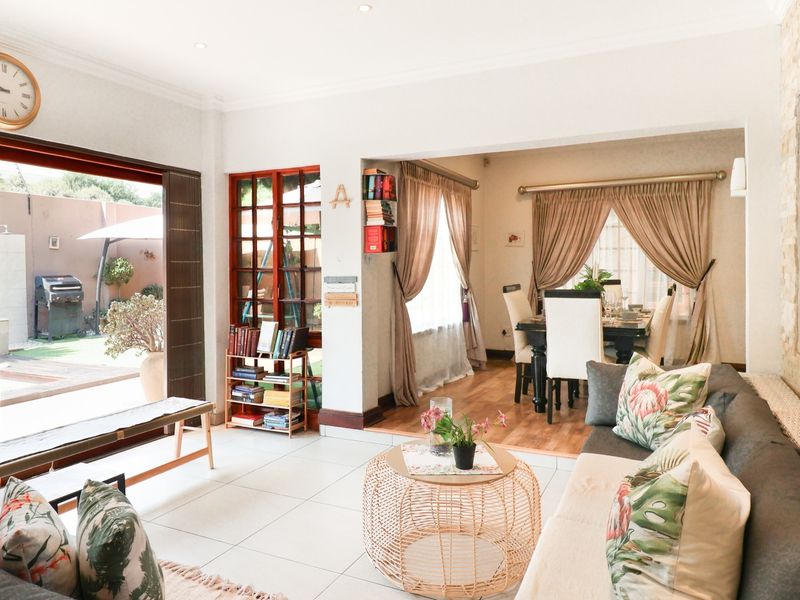 Spacious open-plan living and dining area featuring tiled floors, a stone accent wall, and large sliding doors providing seamless access to the outdoor pool area.