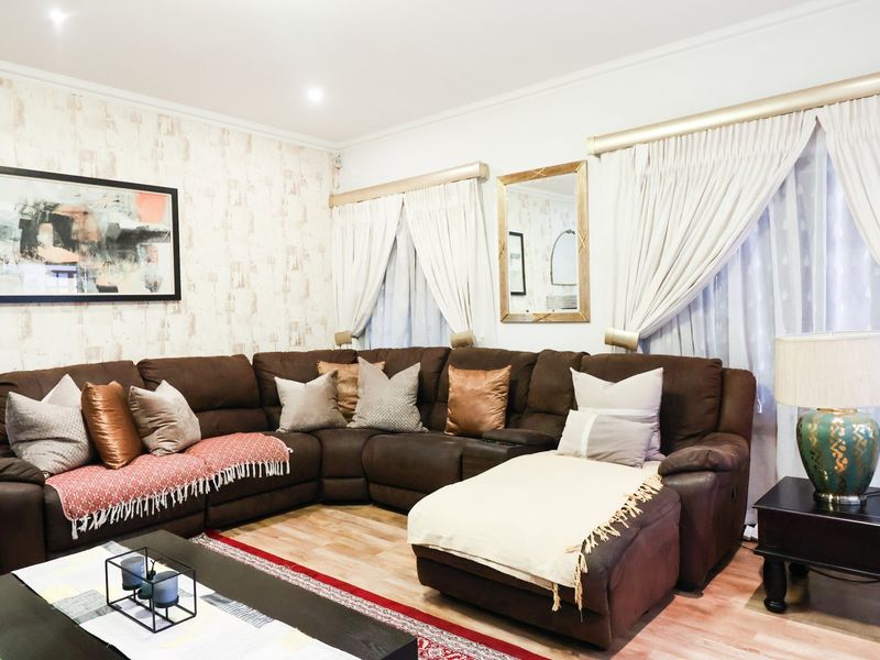 A well-maintained living room featuring laminate flooring, recessed downlights, and neutral wall finishes, providing a comfortable and functional space.