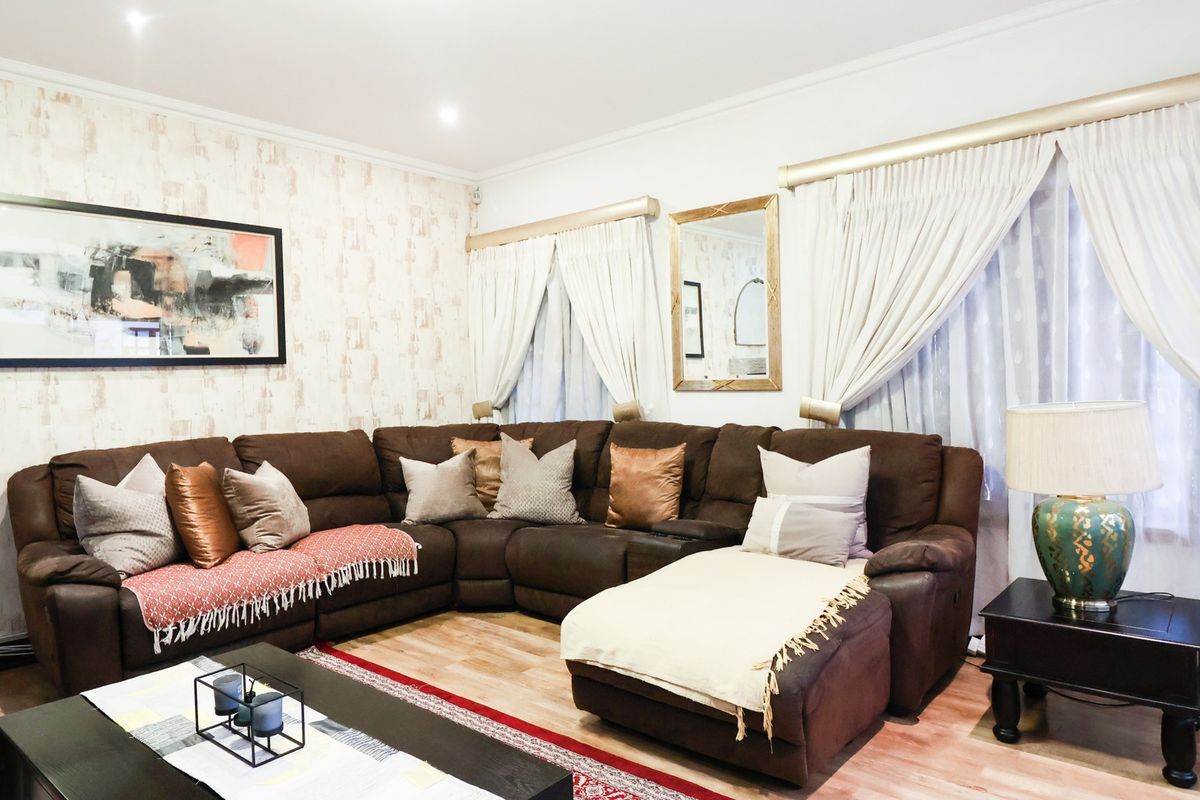 A well-maintained living room featuring laminate flooring, recessed downlights, and neutral wall finishes, providing a comfortable and functional space.