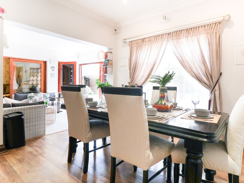 An open-plan dining area featuring laminate flooring and large sliding glass doors that provide access to the adjacent living space and outdoor area.