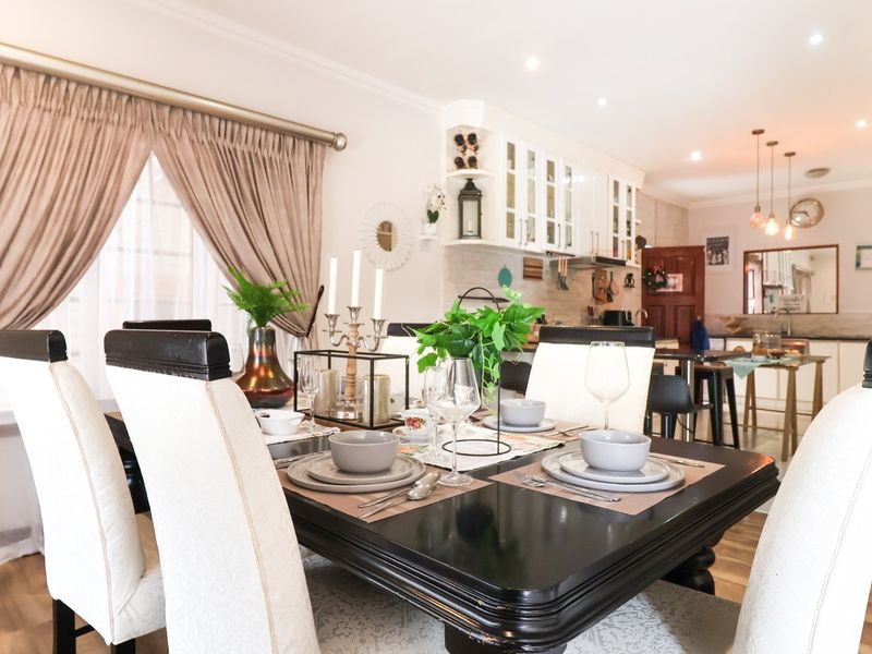 An open-plan dining and kitchen area featuring laminate flooring, recessed lighting, and functional built-in cabinetry, creating a cohesive and connected living space.