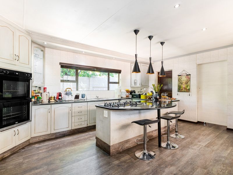 A well-maintained kitchen featuring a central island with a gas cooktop, built-in double oven, ample cabinetry, and modern recessed lighting.