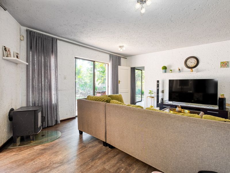 A living room featuring textured walls, laminate flooring, and a wood-burning stove, with direct access to the garden through sliding glass doors.