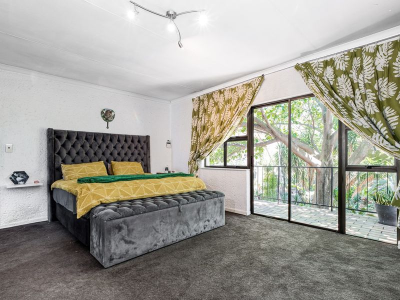 Spacious bedroom featuring textured walls, dark carpeting, and a large sliding glass door providing access to an outdoor balcony area.