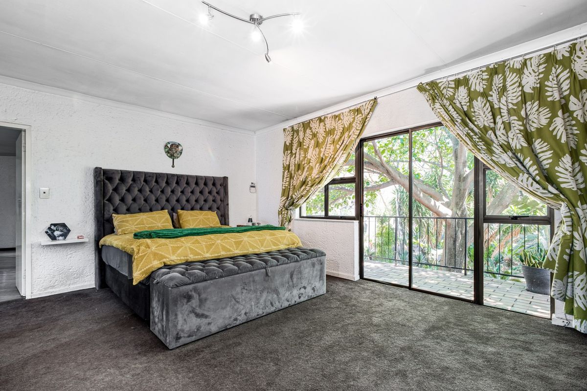 Spacious bedroom featuring textured walls, dark carpeting, and a large sliding glass door providing access to an outdoor balcony area.