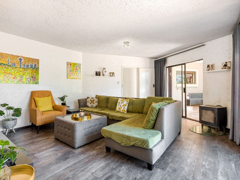 A comfortable living room featuring wood-look laminate flooring, a built-in wood-burning fireplace, and sliding glass doors providing access to the outdoor area.