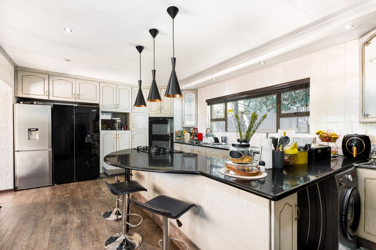 A well-appointed kitchen featuring dark granite countertops, built-in cabinetry, a gas hob, and a double oven, complemented by modern pendant lighting.