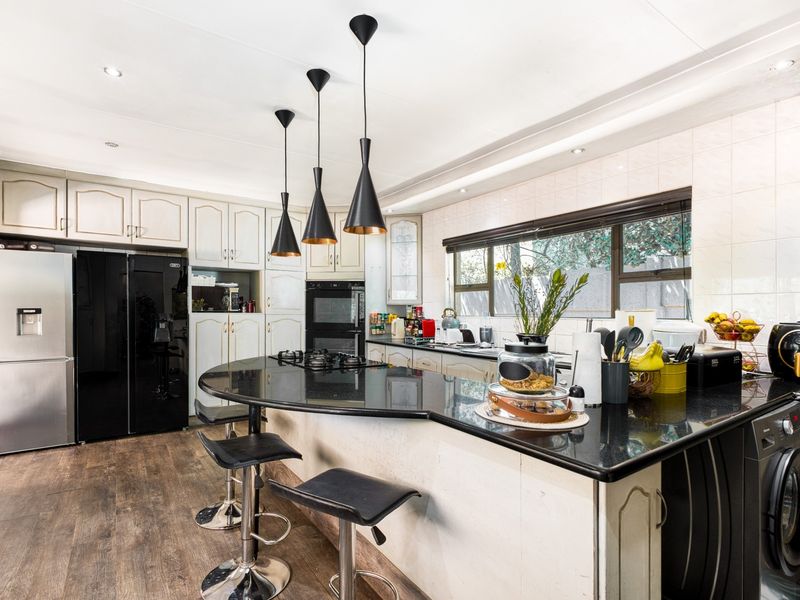 A well-appointed kitchen featuring dark granite countertops, built-in cabinetry, a gas hob, and a double oven, complemented by modern pendant lighting.