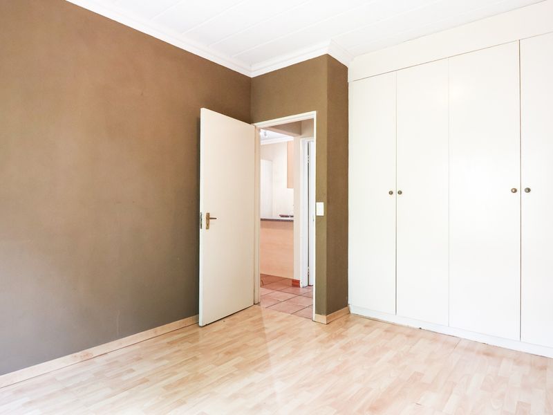 An empty bedroom featuring laminate flooring, built-in cupboards, and neutral wall finishes, offering a blank canvas for personalization.
