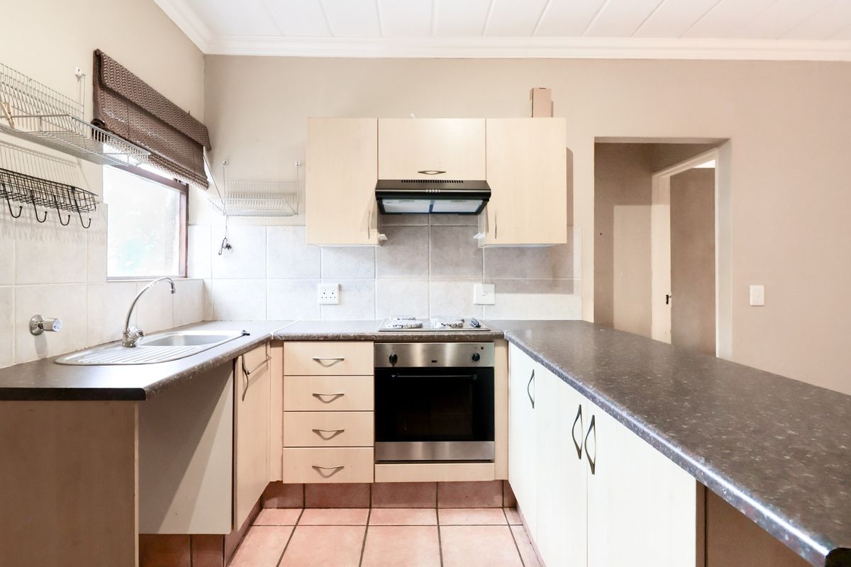 A functional kitchen featuring laminate cabinetry, a stainless steel oven with gas hob, tiled backsplash, and a breakfast bar counter.