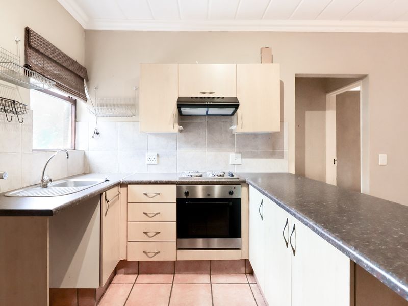 A functional kitchen featuring laminate cabinetry, a stainless steel oven with gas hob, tiled backsplash, and a breakfast bar counter.