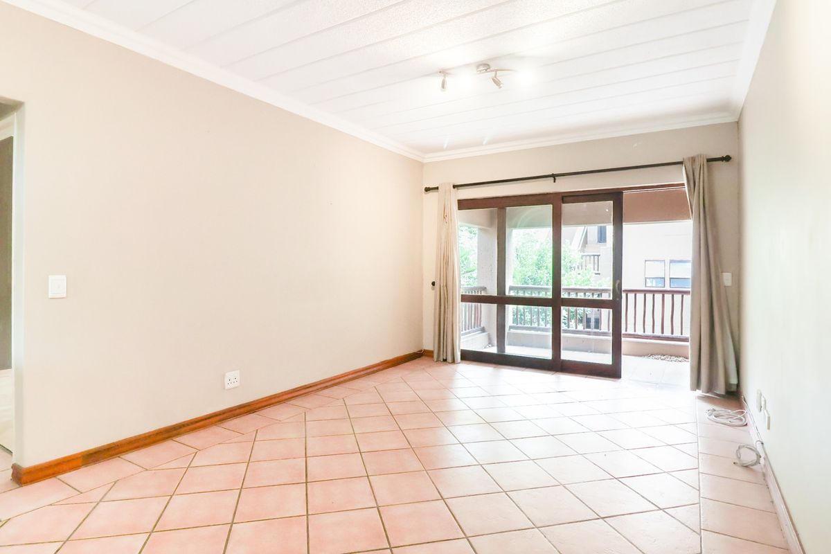 An empty living room featuring tiled flooring, a sliding glass door leading to a balcony, and a paneled ceiling.