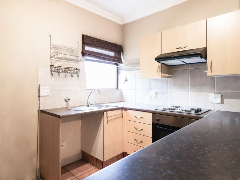 A functional kitchen featuring laminate cabinetry, dark countertops, a built-in oven with gas hob, and a tiled backsplash.