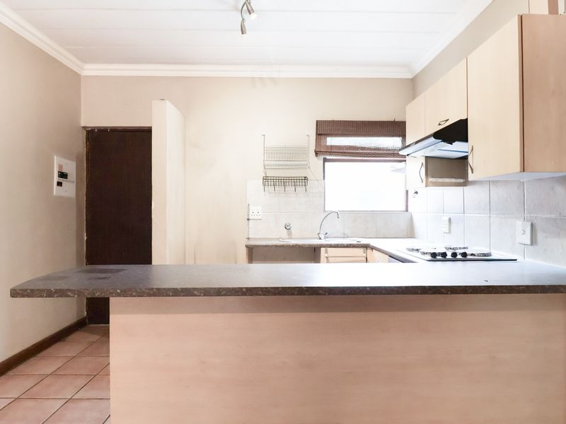 A functional kitchen featuring built-in cabinetry, a breakfast bar, tiled backsplash, and integrated hob with extractor fan.