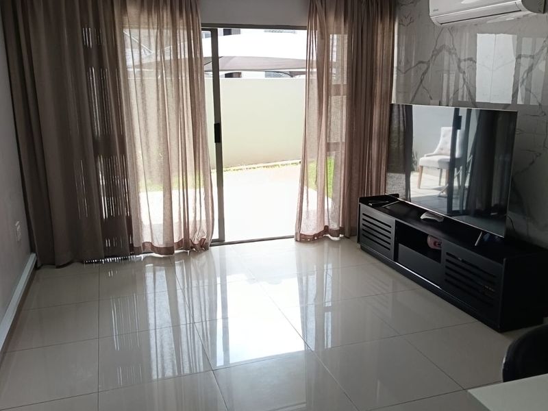 Modern living room featuring polished porcelain floor tiles, marble-effect feature wall, split-system air conditioning, and sliding glass doors leading to an outdoor area.