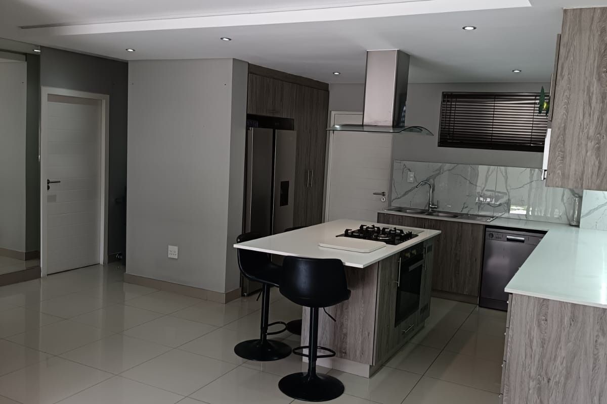 Modern kitchen featuring a central island with a gas hob, sleek cabinetry, marble-look backsplash, and high-quality tiled flooring with recessed lighting.