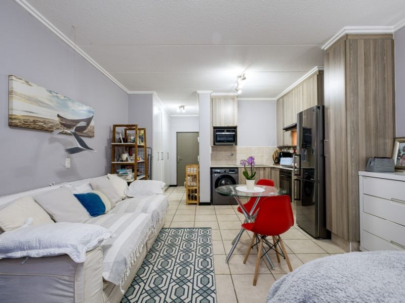 Open-plan living area featuring tiled flooring, built-in kitchen cabinetry, and integrated appliances, creating a functional and connected space.