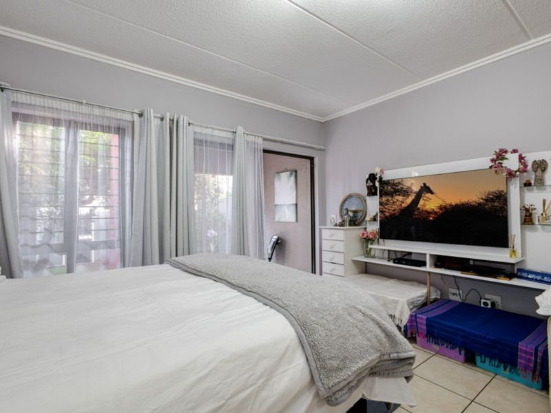 A bedroom featuring tiled flooring, a built-in wall unit, and a sliding glass door providing access to an outdoor area.