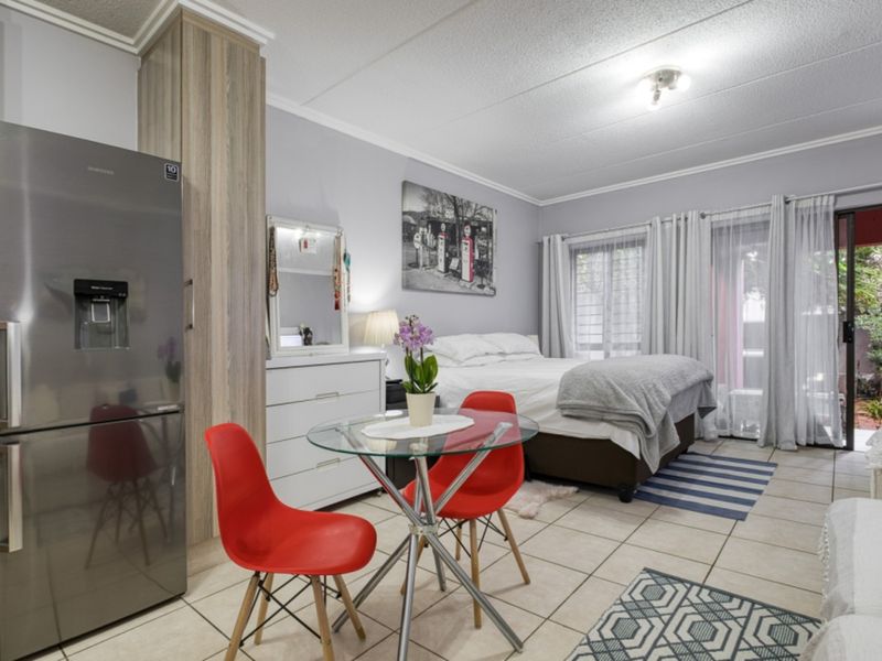 Open-plan studio apartment featuring tiled flooring, built-in cabinetry, and sliding glass doors providing access to an outdoor area.
