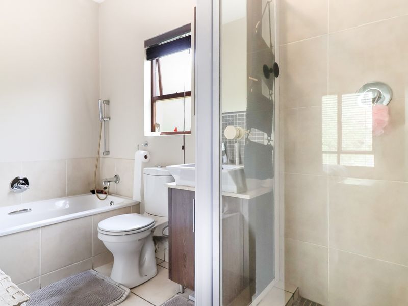 A functional bathroom featuring a built-in bathtub, separate shower enclosure, toilet, and a vanity cabinet with a basin.