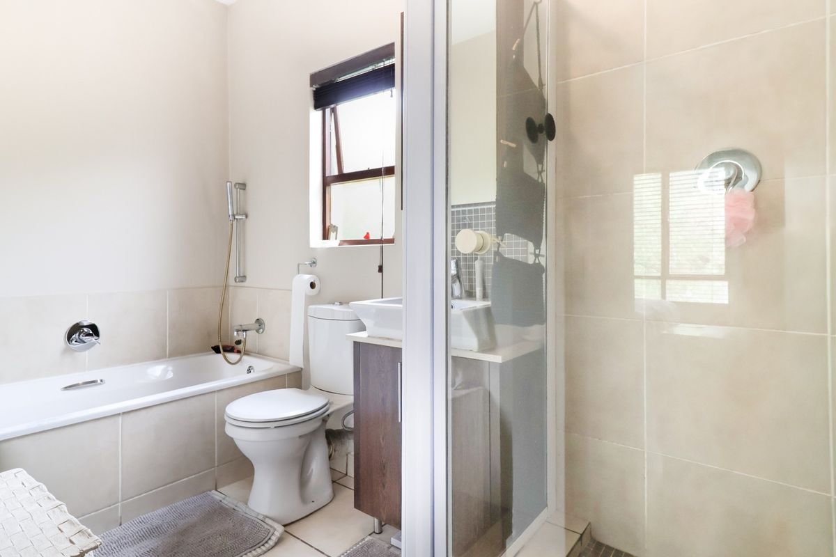 A functional bathroom featuring a built-in bathtub, separate shower enclosure, toilet, and a vanity cabinet with a basin.