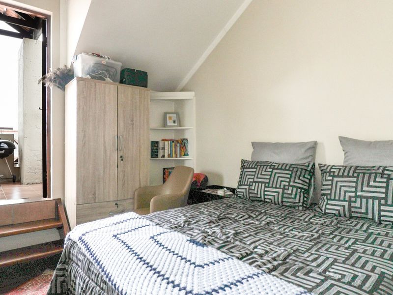 Bedroom featuring a sloped ceiling, built-in shelving, and direct access to an outdoor balcony area via a small step.