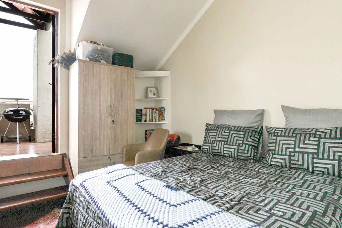 Bedroom featuring a sloped ceiling, built-in shelving, and direct access to an outdoor balcony area via a small step.