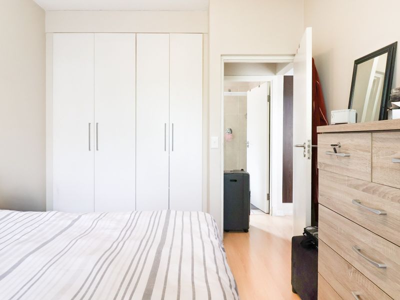 A well-maintained bedroom featuring built-in cupboards, laminate flooring, and direct access to an en-suite bathroom.