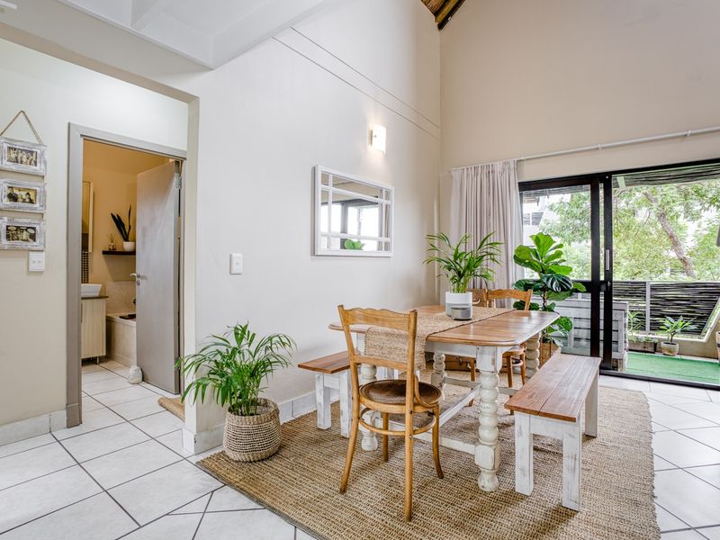 Open plan dining area featuring high vaulted ceilings, tiled flooring, and direct access to a private balcony through sliding glass doors.