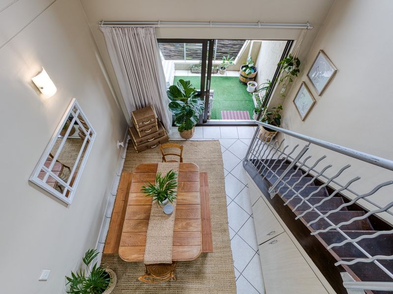 Open-plan living area featuring a staircase with metal balustrade, under-stair storage, and sliding glass doors leading to an outdoor patio space.