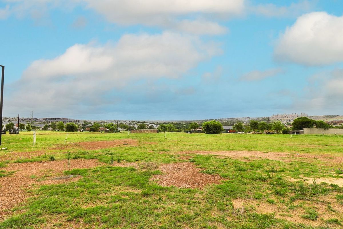 A vacant residential plot of land featuring open grass and a street light, situated in a developed neighborhood.