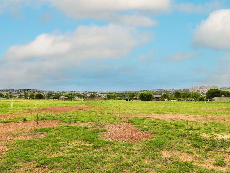 A vacant residential plot of land featuring open grass and a street light, situated in a developed neighborhood.