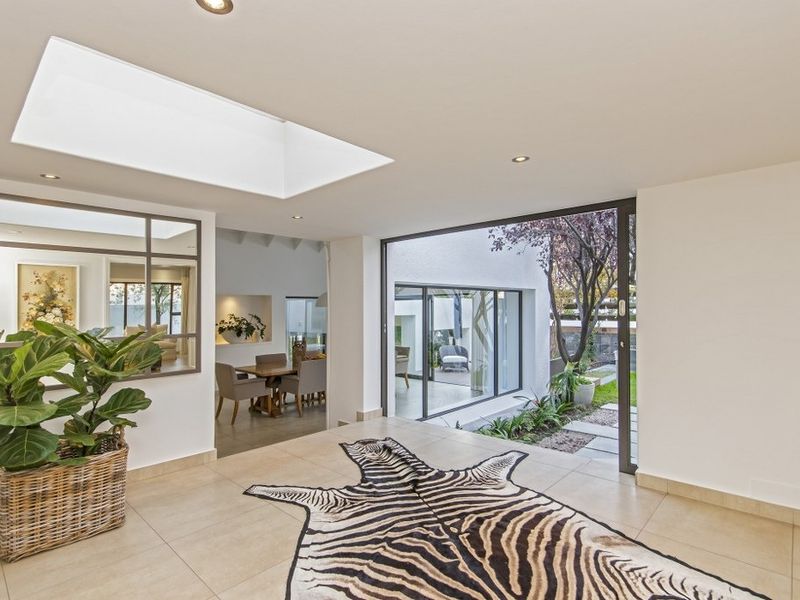 Bright and modern entrance hall featuring large skylights, tiled flooring, and seamless indoor-outdoor flow through expansive sliding glass doors.