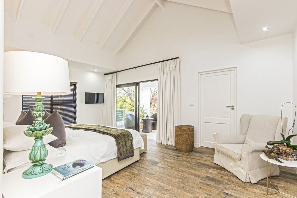 Spacious bedroom featuring a high vaulted ceiling, timber-look flooring, and sliding glass doors that open onto a private balcony.