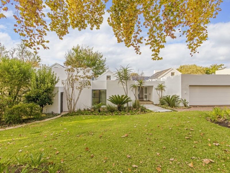 A well-maintained modern white house featuring a landscaped front garden, paved entrance walkway, and an integrated single garage.