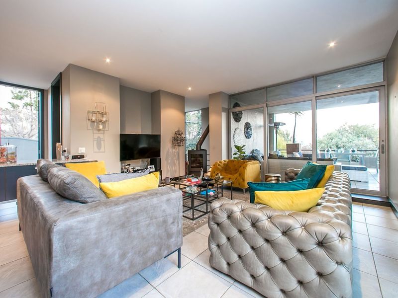 Spacious open-plan living area featuring a modern freestanding fireplace, large sliding glass doors leading to a patio, and contemporary tiled flooring.