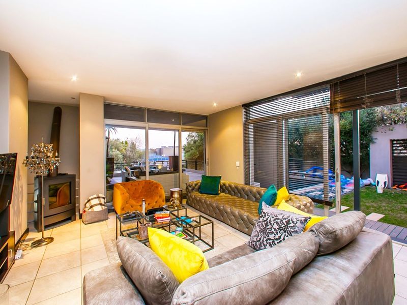 Spacious living room featuring tiled flooring, a modern freestanding fireplace, and large sliding glass doors providing seamless access to the outdoor garden area.