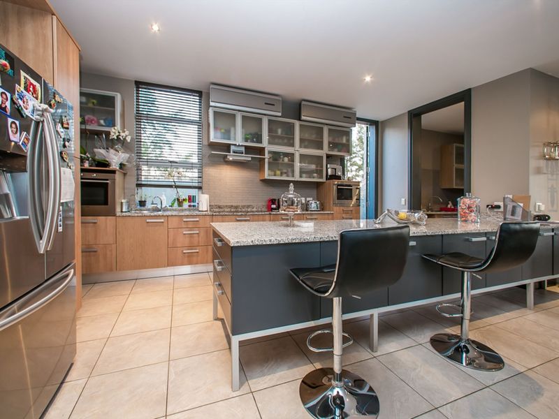 Modern kitchen featuring a central island with granite countertops, ample cabinetry, built-in appliances, and tiled flooring, offering a functional and contemporary cooking space.