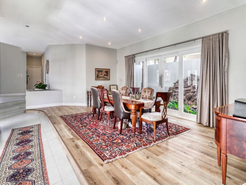 Spacious dining room featuring a raised timber floor platform, recessed downlights, and large sliding glass doors providing access to the outdoor area.