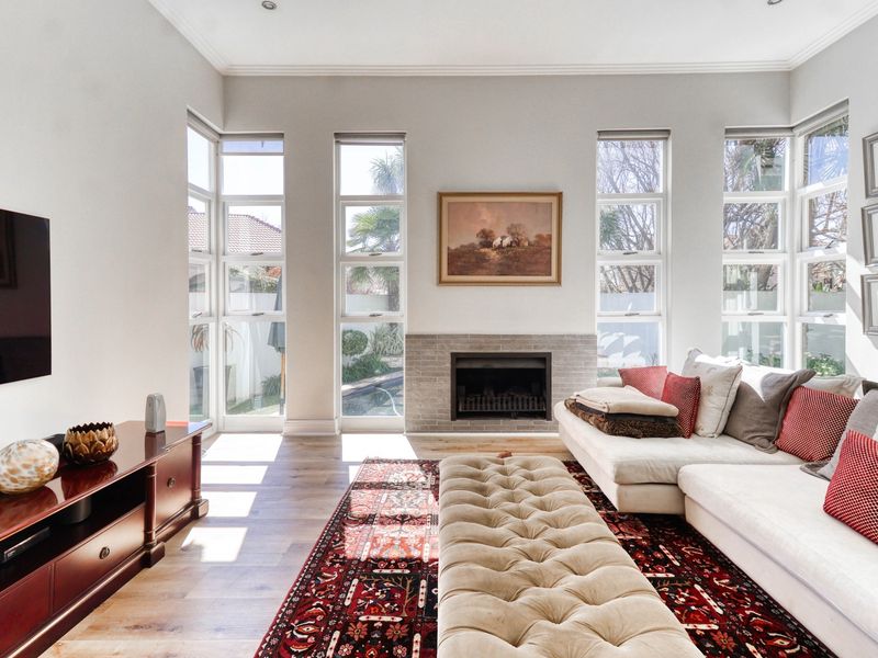 Bright and spacious living room featuring timber flooring, a central fireplace, and large windows that provide ample natural light.